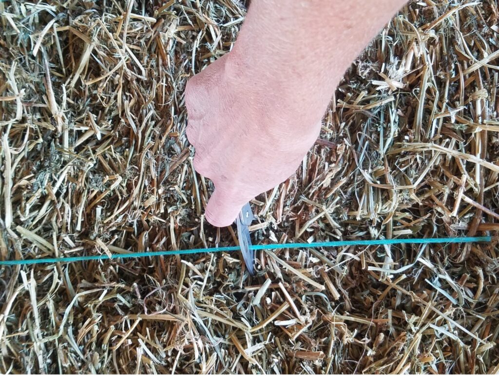 hay bale twine being cut on square hay bale